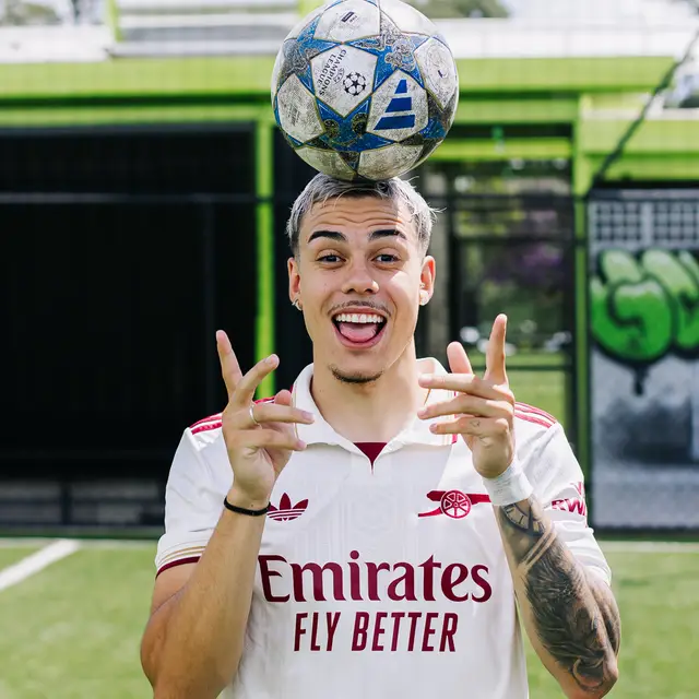 Dudu Footz balancing a football on his head on a pitch