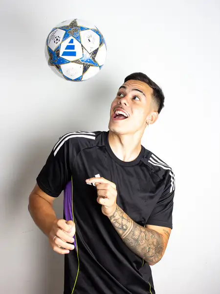 Dudu Footz smiling with a football floating above his head, in a studio
