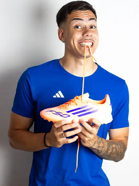 Dudu Footz biting a boot lace with an exaggerated funny expression