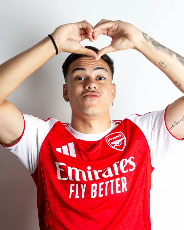 Dudu Footz making a heart shape with his hands, wearing an Arsenal jersey